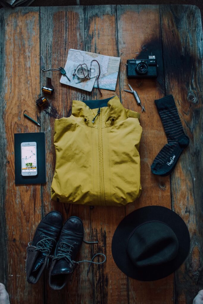 Flat lay of Alaska trip gear: rain jacket, boots, hat, map, and compass