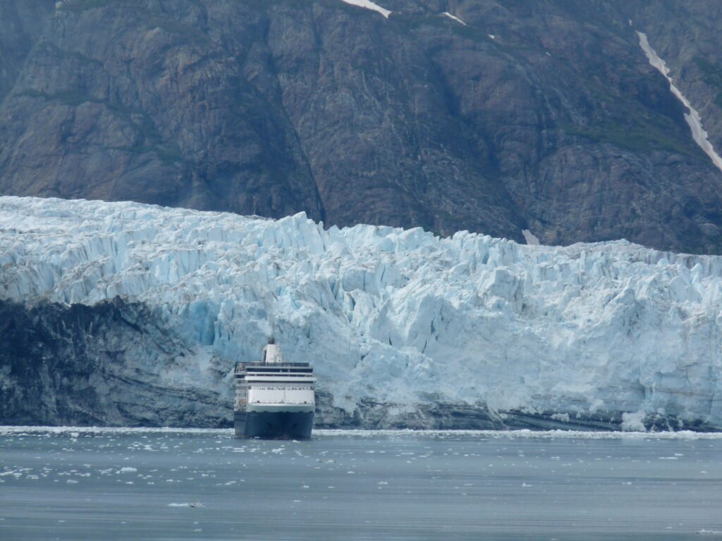 Cruise ship dwarfed by a glacier face in Glacier Bay, Alaska