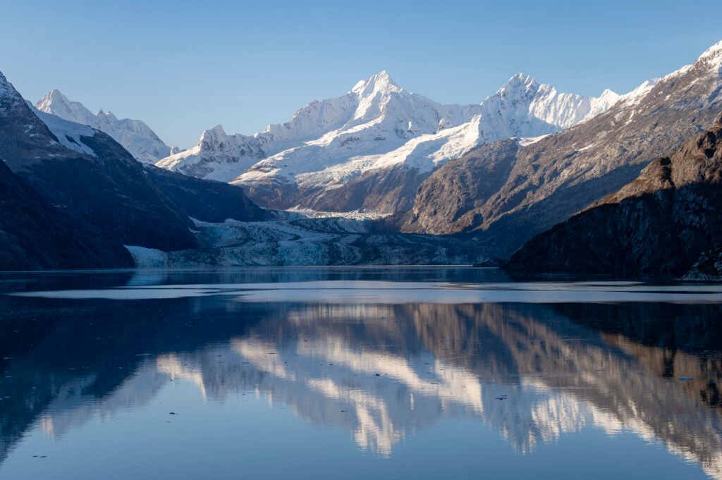 Glacier and snow peaks mirrored in calm water, Glacier Bay National Park, Alaska