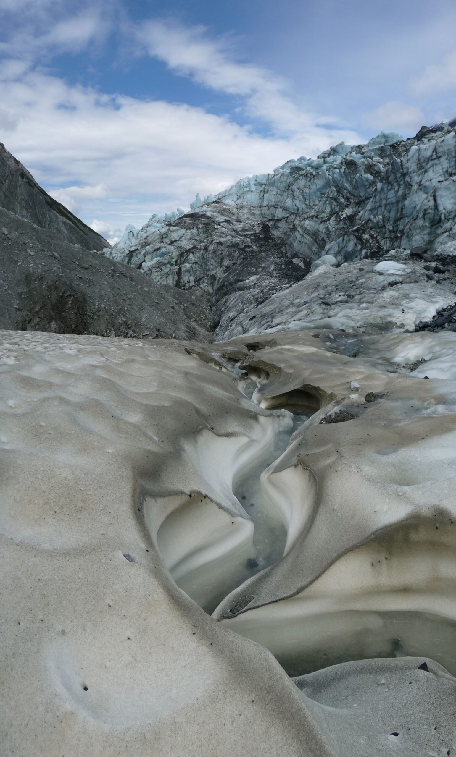 Meltwater channels carved across a glacier's icy surface below the ice terminus in Glacier Bay, Alaska